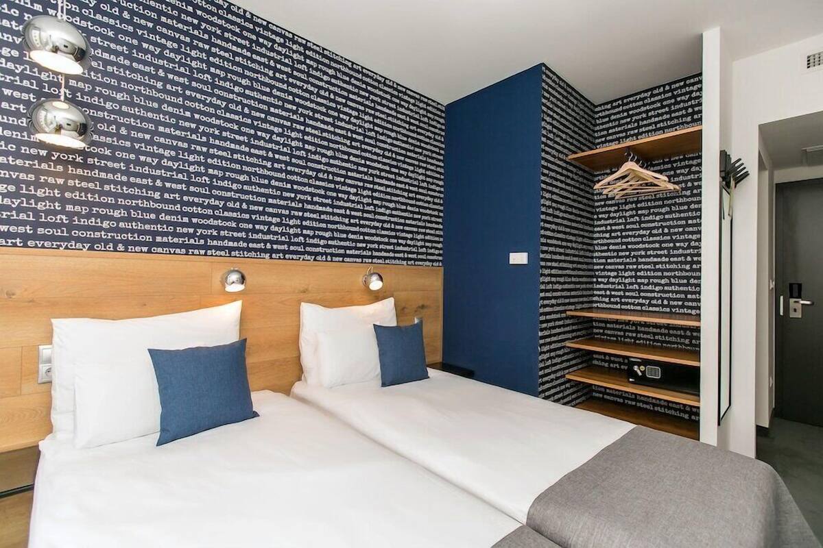 A hotel room with a large bed, two bedside tables, a wardrobe, and a wall with text.