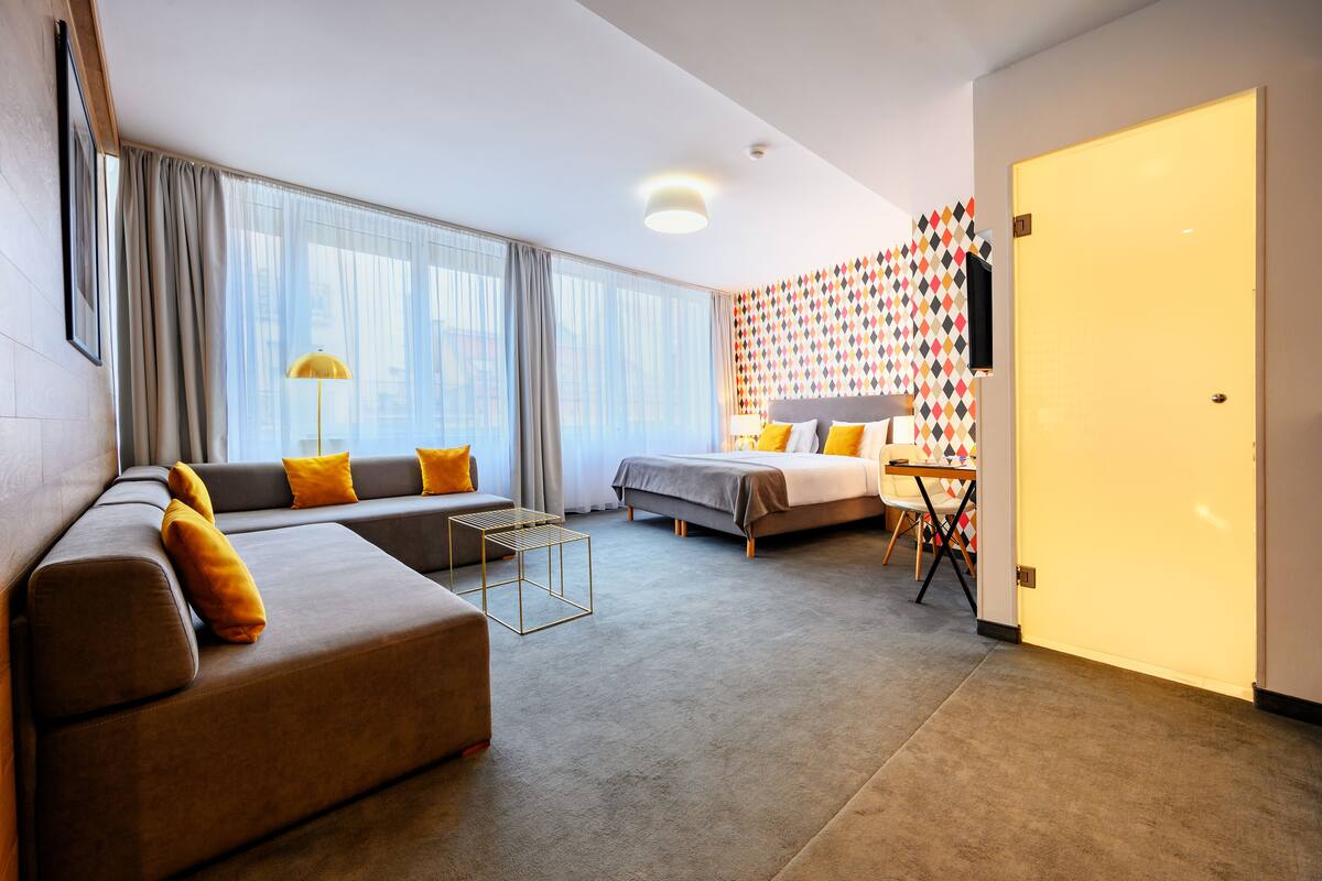A modern hotel room with a sofa, bed, and a small table.