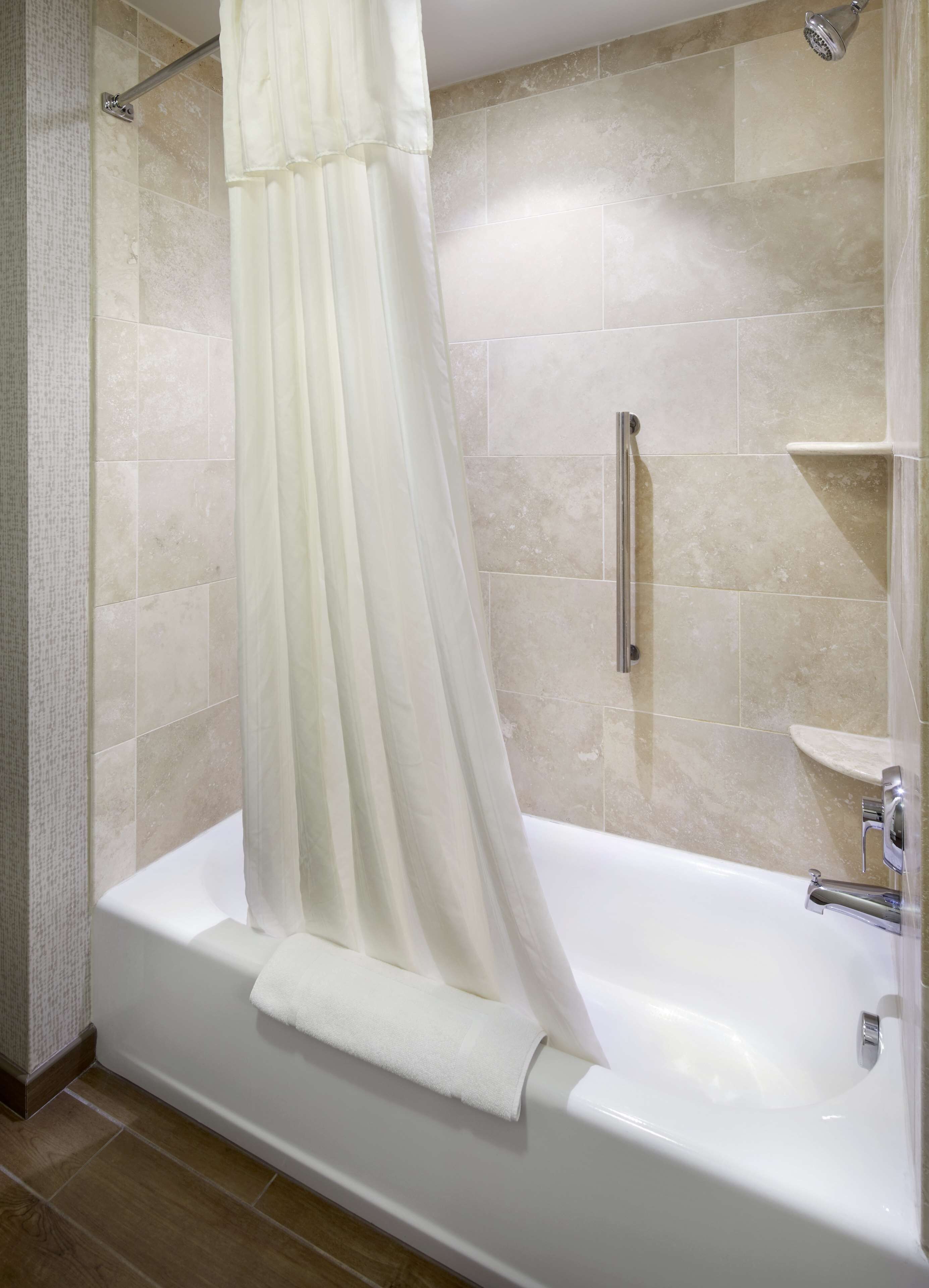 A bathroom with a bathtub, a shower curtain, and tiled walls.