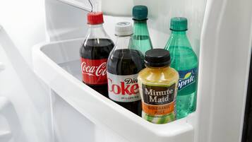 Una estantería de refrigerador con cuatro botellas: Coca-Cola, Diet Coke, Jugo Naranja 100% Minute Maid y Sprite.
