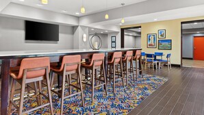 En modern hotellobby med en bardisk, sittplatser och konstverk på väggarna.