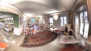 A spacious room with a large dining area, a fireplace, and a view of the street. - Hotel Corona Grossa (Balangero)