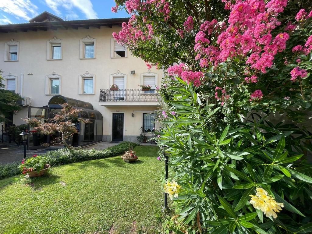 Un edificio con un giardino antistante, un balcone con ringhiera e una porta.