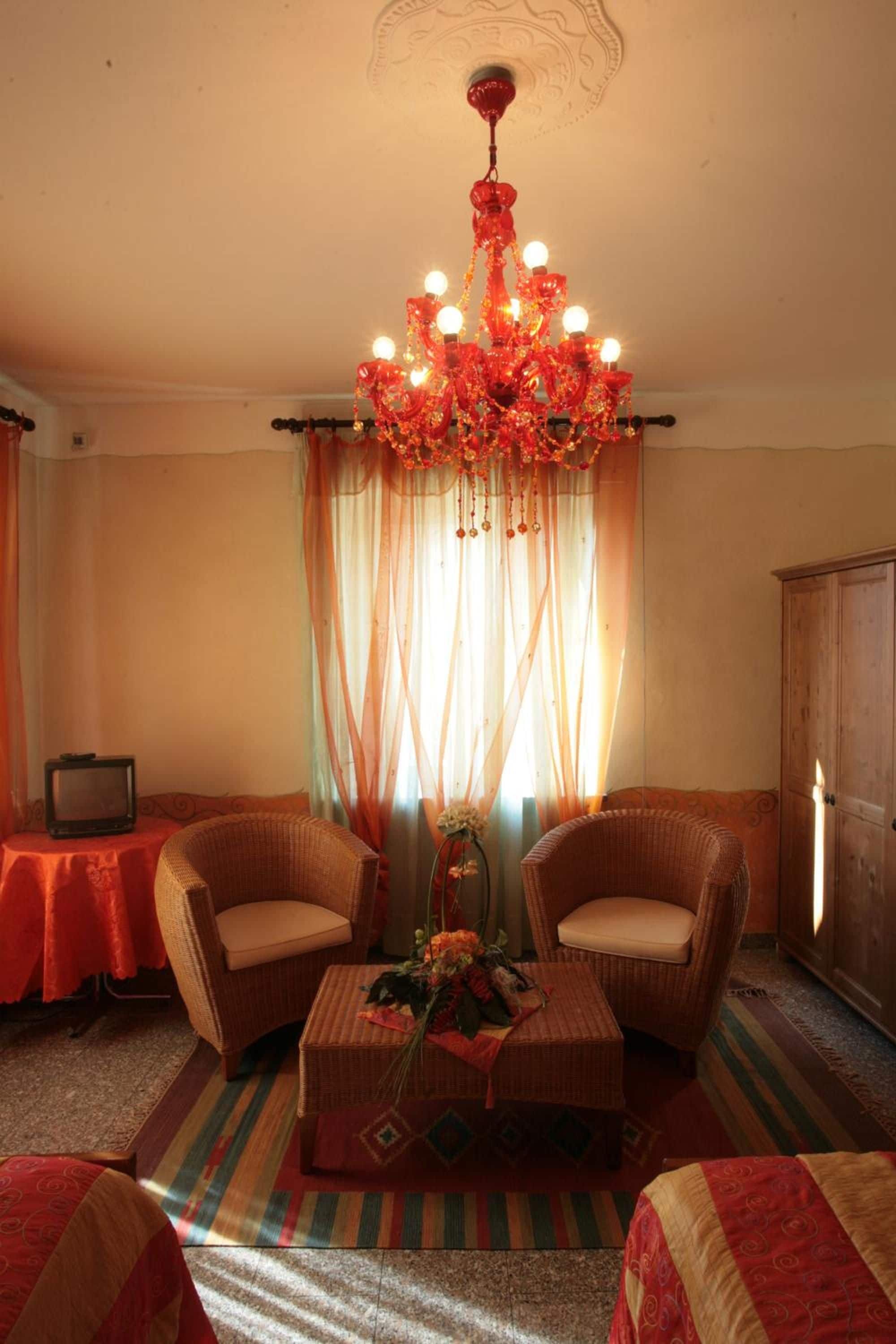 Una habitación con dos sillones de mimbre, una mesita, un televisor y un candelabro.