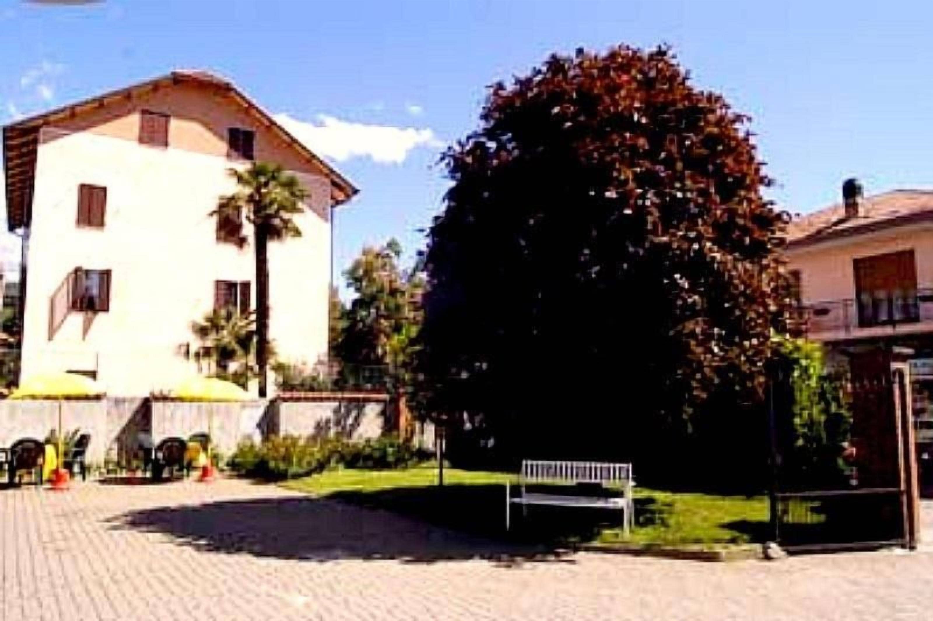 A building with a tiled ground, a bench, and a tree.