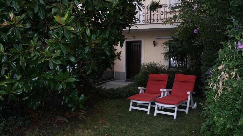 Um jardim com uma porta, um pequeno caminho e duas cadeiras vermelhas.