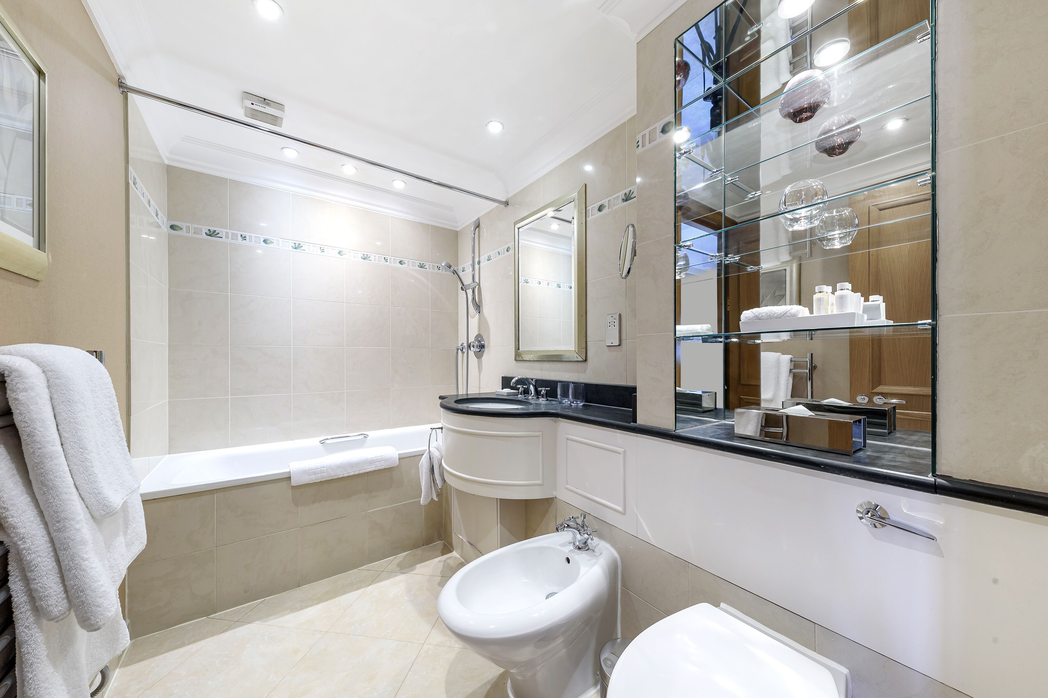 Un baño moderno con bañera, bidé, lavamanos y un espejo grande.