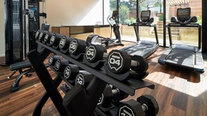 Une salle de sport équipée de matériel d’exercice, de tapis de course et d’haltères.