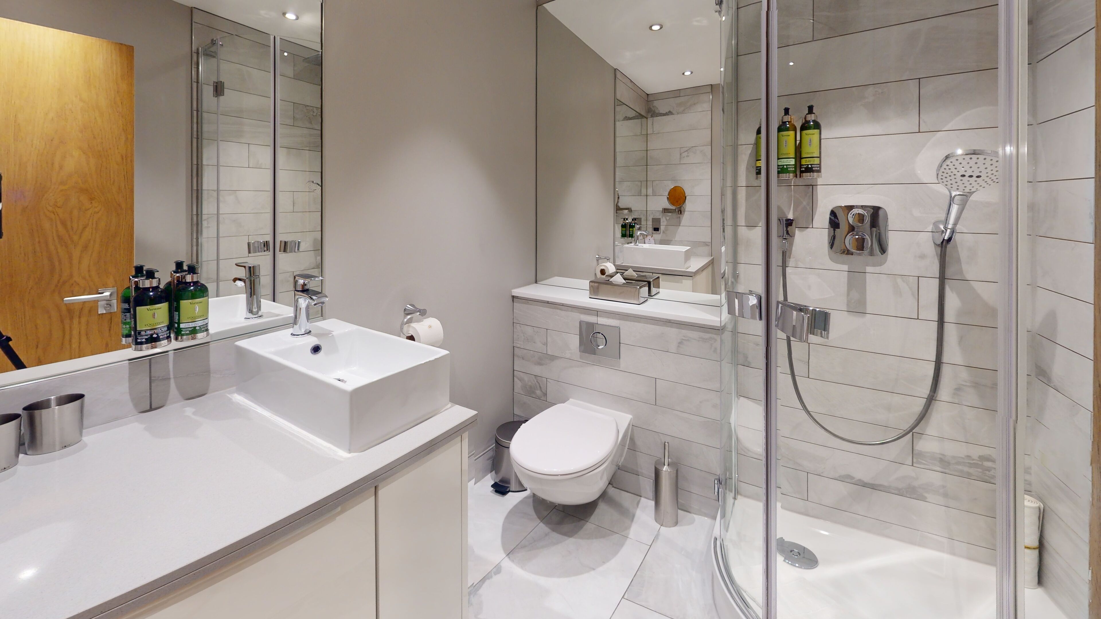 A modern bathroom with a large white sink, a toilet, and a glass-enclosed shower area.