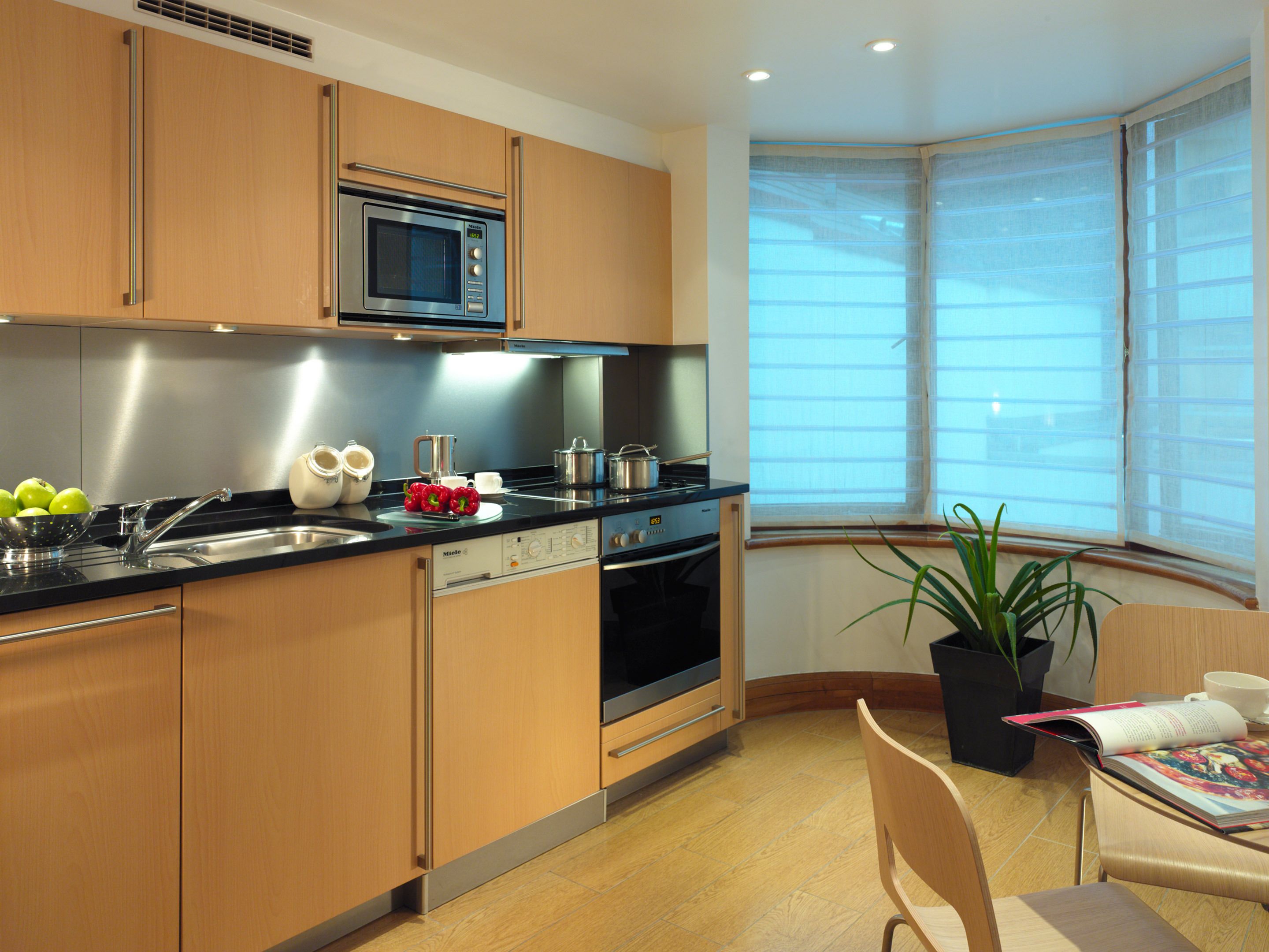 A modern kitchen with wooden cabinets, stainless steel appliances, and a window providing natural light.