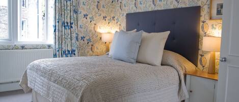 Une chambre à coucher avec un grand lit, un papier peint à motifs floraux et deux lampes de chevet.
