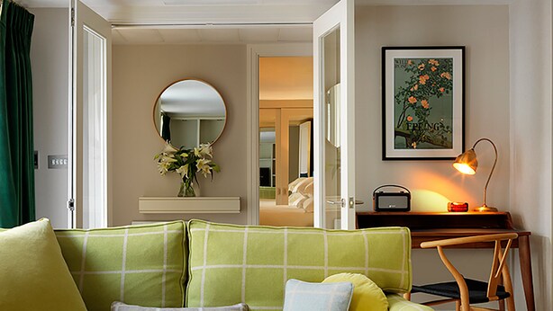Un canapé vert, avec un miroir et un tableau encadré accroché au mur.