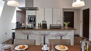 Une cuisine moderne dotée d’un îlot central, de tabourets de bar et d’une table à manger où sont servis des plats pour le petit-déjeuner.