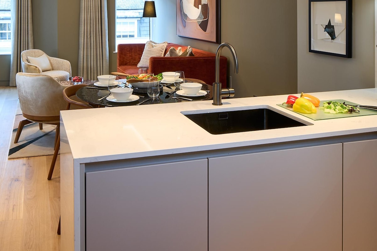 A modern kitchen with a built-in sink, dining area with chairs, and a view of the street.