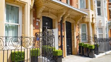 Classic townhouse with a black door, white-framed window, and decorative stonework.