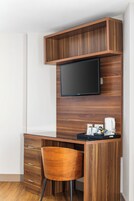 Un espacio de oficina moderno con escritorio integrado, una silla, un televisor de pantalla plana y una máquina de café.