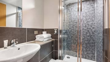 A modern bathroom with a glass-enclosed shower, a sink, and a toilet.
