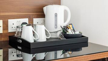 Un área de cocina moderna con cafetera, tetera y una bandeja con utensilios.