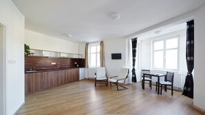 A modern kitchen with wooden cabinets, a dining area with a table and chairs, and large windows with curtains. - Hostel Foster (Marianske Lazne)