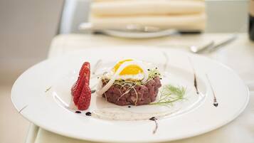 Um prato com uma porção de steak tartare, uma morango e um ovo pochê.