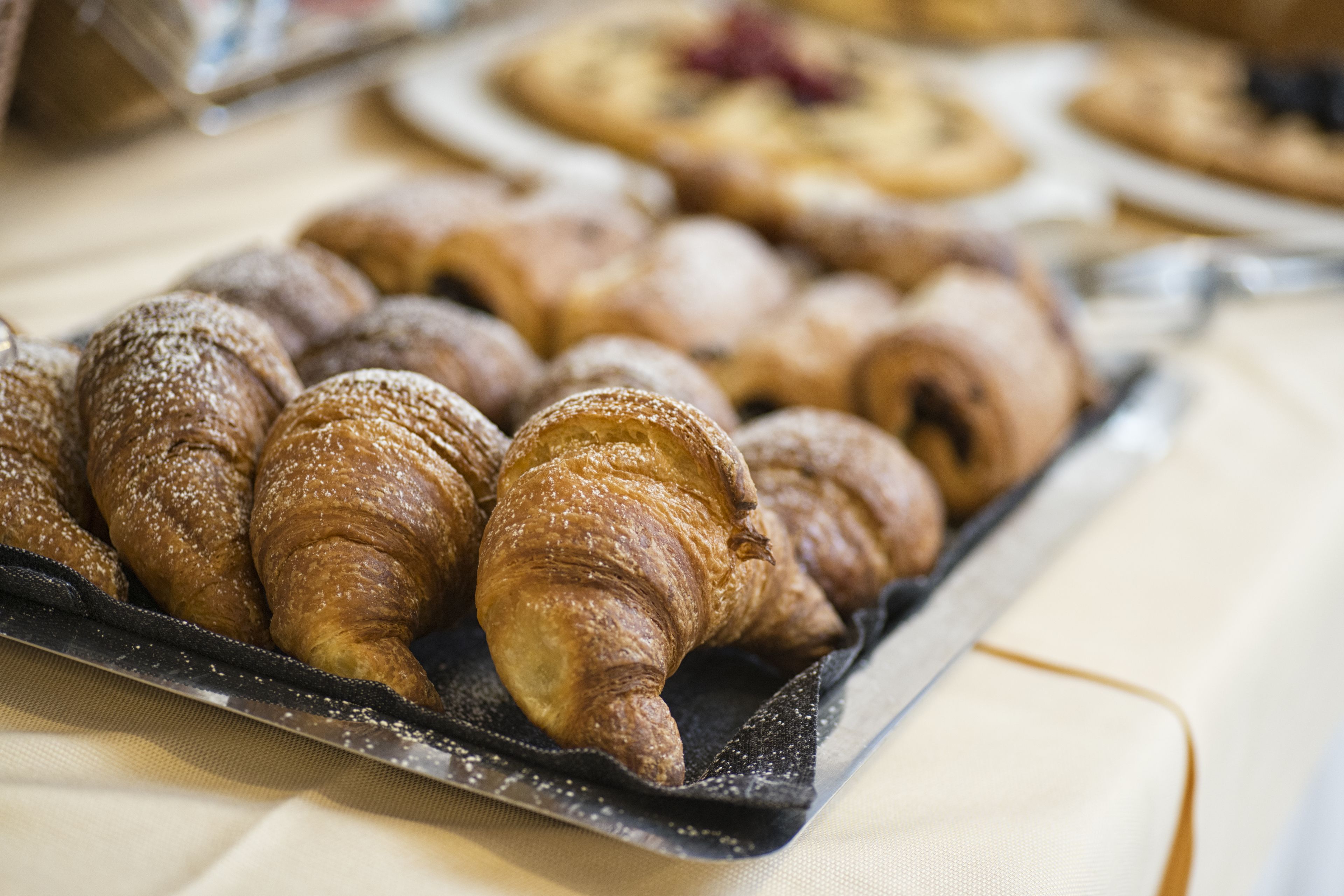 A tray of assorted pastries, including croissants and other baked goods, on a table.