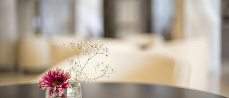 Un florero de vidrio transparente con flores sobre una mesa redonda en una habitación bien iluminada.