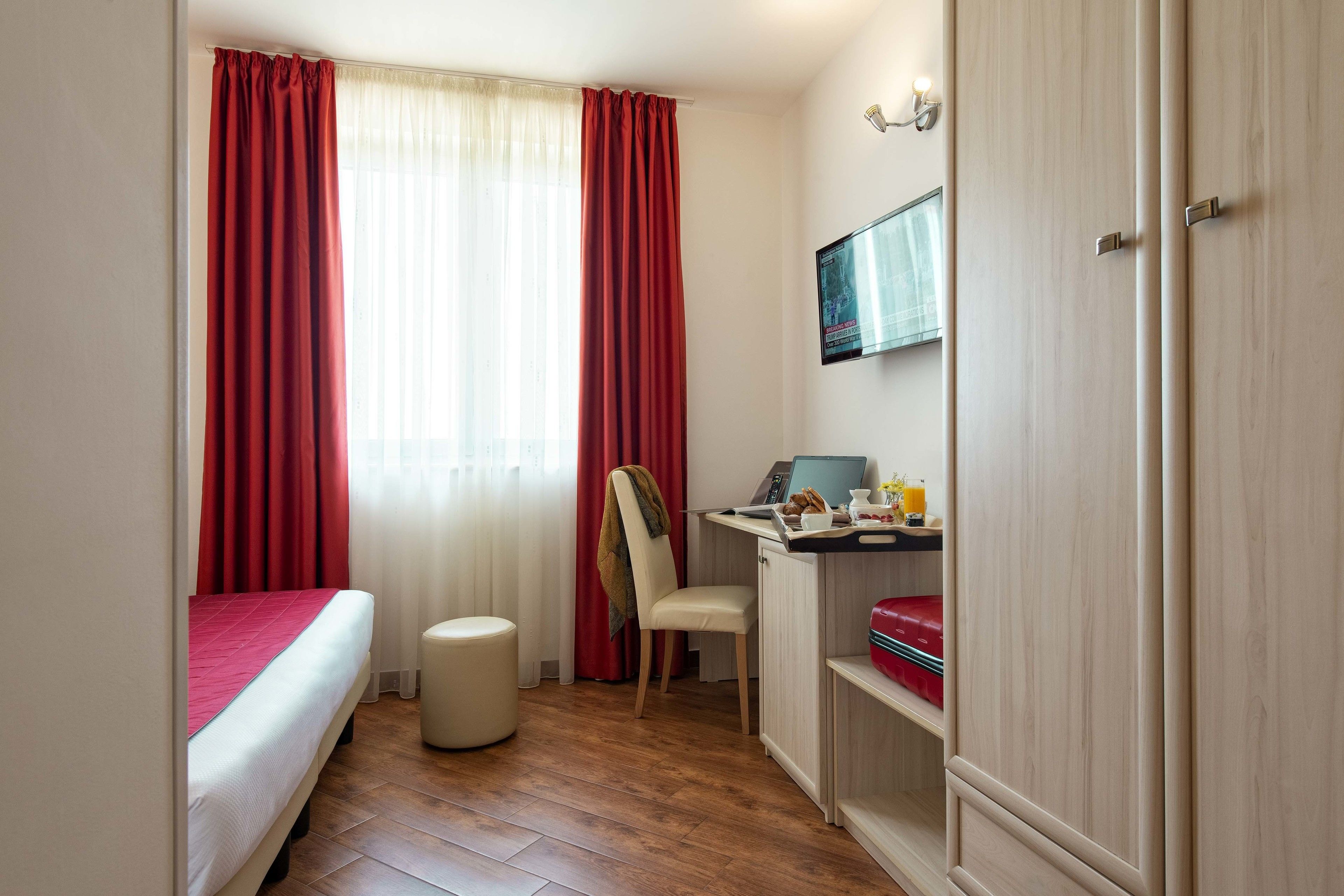 A bedroom with a bed, a desk with a computer, a chair, and a wardrobe.