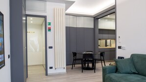 Un interior moderno con comedor, un sofá verde y una cocina al fondo.