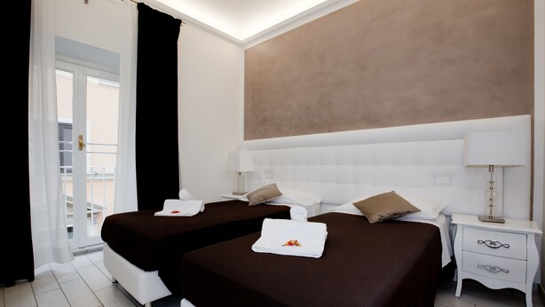 Habitación de hotel con dos camas, un ventanal grande y vistas al exterior.