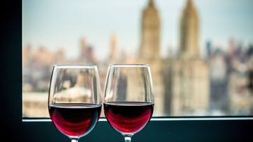 Two wine glasses with red wine on a windowsill, with a blurred cityscape in the background.