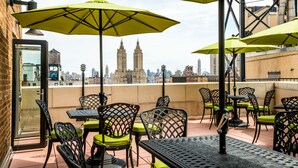 A rooftop terrace with outdoor seating, including tables and chairs, and large umbrellas providing shade. - Hotel Beacon (New York)