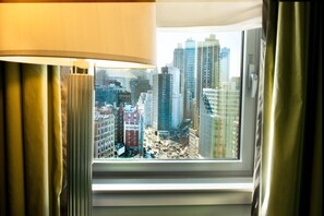 A window with a view of a cityscape, curtains partially drawn, and a lamp on the left. - Hotel Beacon (New York)