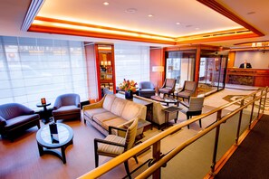 A modern hotel lobby with a seating area, a reception desk, and a glass elevator. - Hotel Beacon (New York)