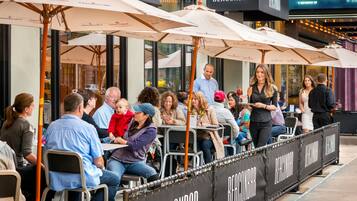 An outdoor seating area with umbrellas and tables, a sign for Beacon Bar, and people dining.
