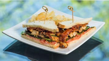 A sandwich with a toothpick on a plate, accompanied by chips.