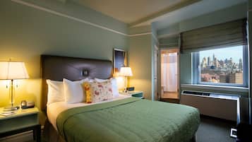 A hotel room with a bed, two bedside tables with lamps, a city view through the window, and a door leading to another room.