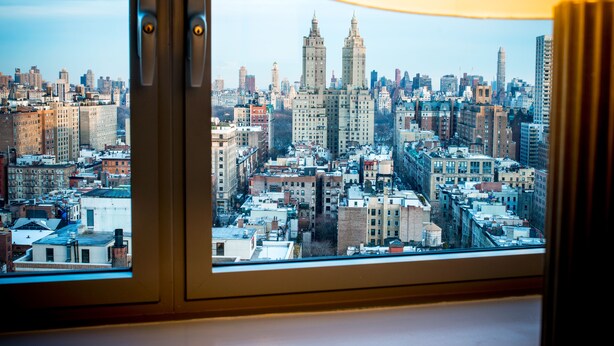 A cityscape through a window with a view of tall buildings and a lamp. - Hotel Beacon (New York)