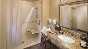 A bathroom with a shower, a sink, a mirror, and a countertop with toiletries.