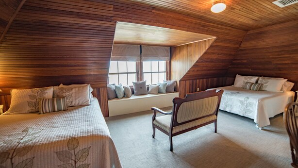 Een gezellige kamer met twee bedden, een bankje en een houten plafond.