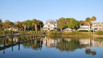 A waterfront property with a dock, a large house, and surrounding palm trees.