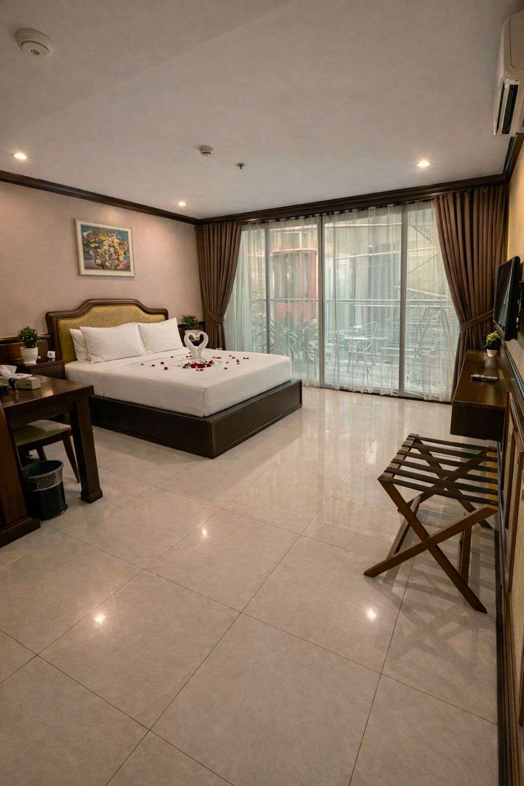 Een moderne hotelkamer met een groot bed, een bureau, een stoel en uitzicht op een balkon.
