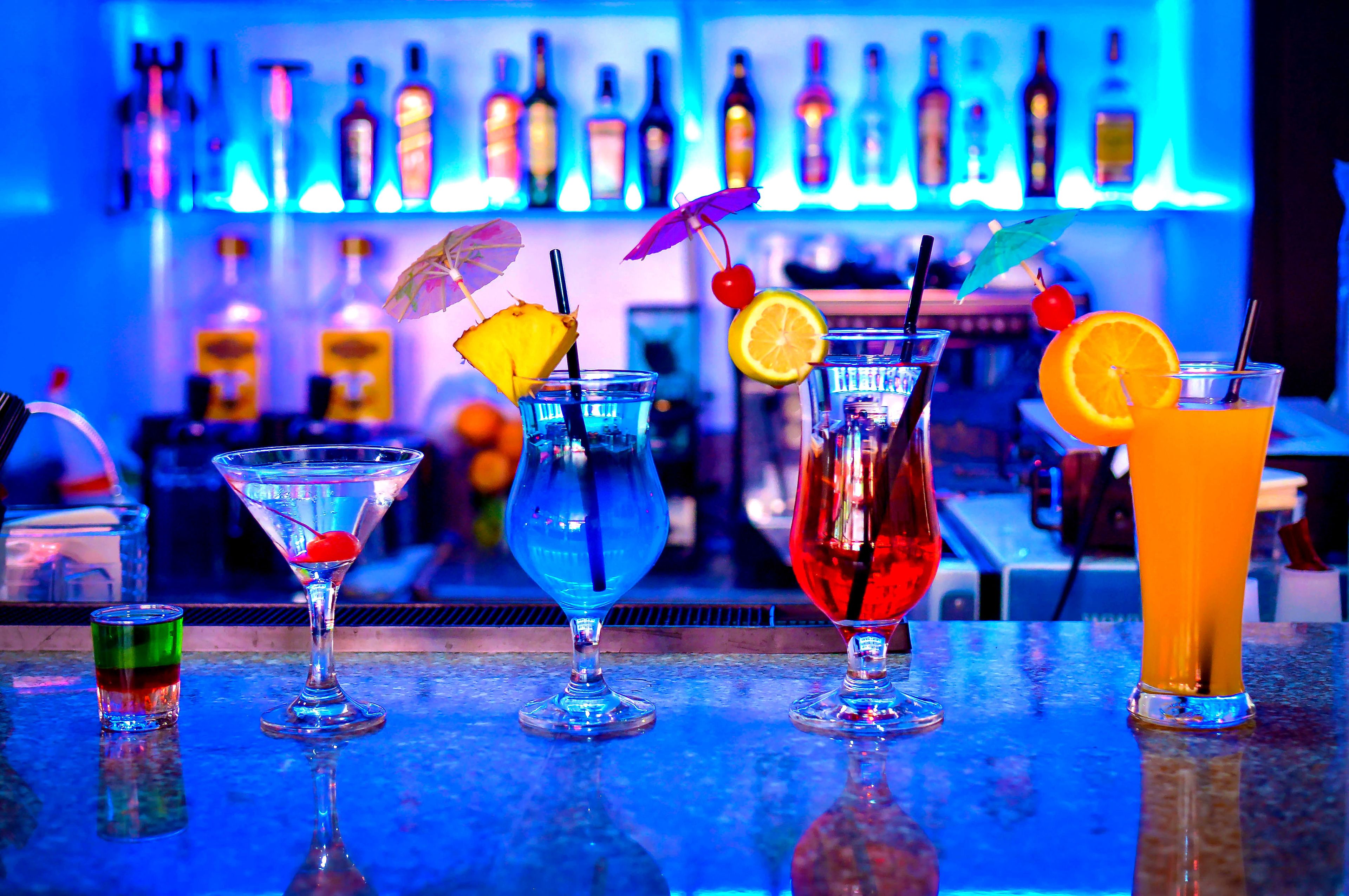 A bar with various drinks, including cocktails with garnishes like fruit and umbrellas.