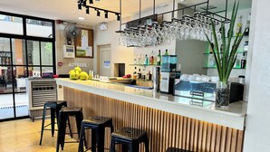 A bar area with stools, a counter with glasses and bottles, and a fan. - Red Coco Inn de Boracay (Boracay Island)