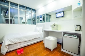 A hotel room with a bed, a small white desk with a computer, a television, and a mini-fridge labeled "Laundry Bag". - Clover Hotel City Center (Yangon)