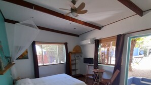 A room with a bed, a desk, a chair, a ceiling fan, and windows. - Caribbean Chillout (Kralendijk)