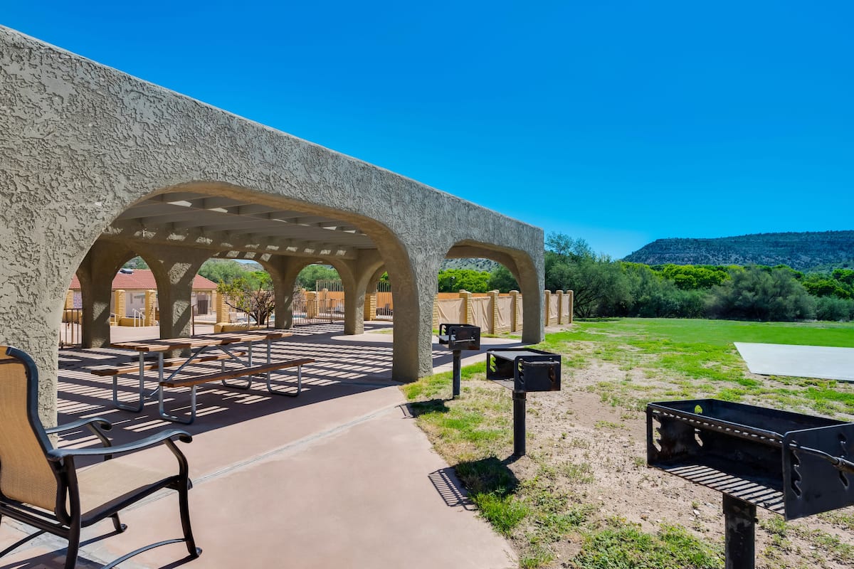 Un patio exterior con mesas de picnic y una parrilla.