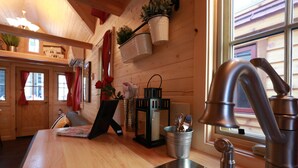Une cuisine avec des murs en bois, un évier en acier inoxydable et une fenêtre donnant sur un immeuble.