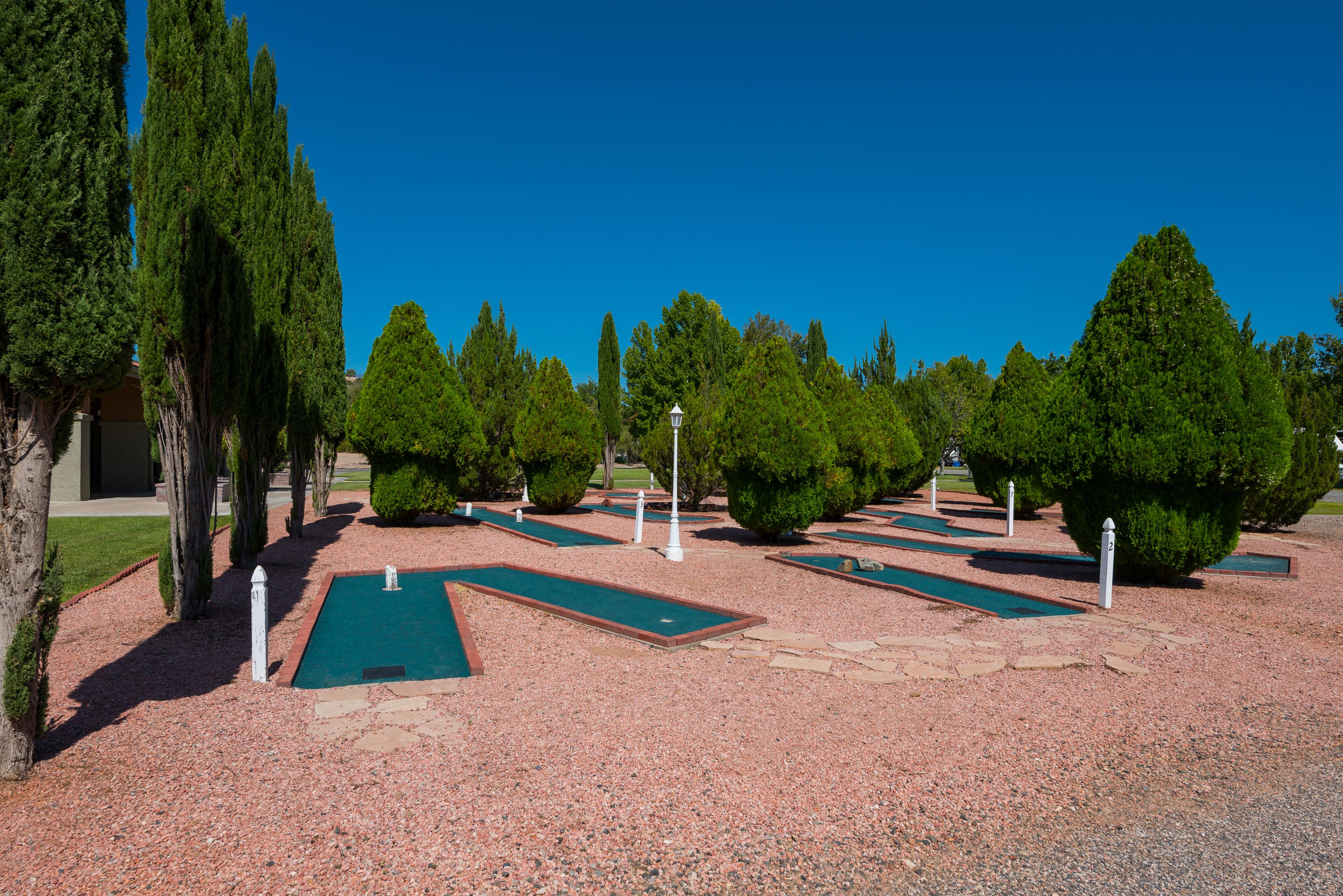 A well-maintained golf course with neatly arranged putting greens and surrounding trees.
