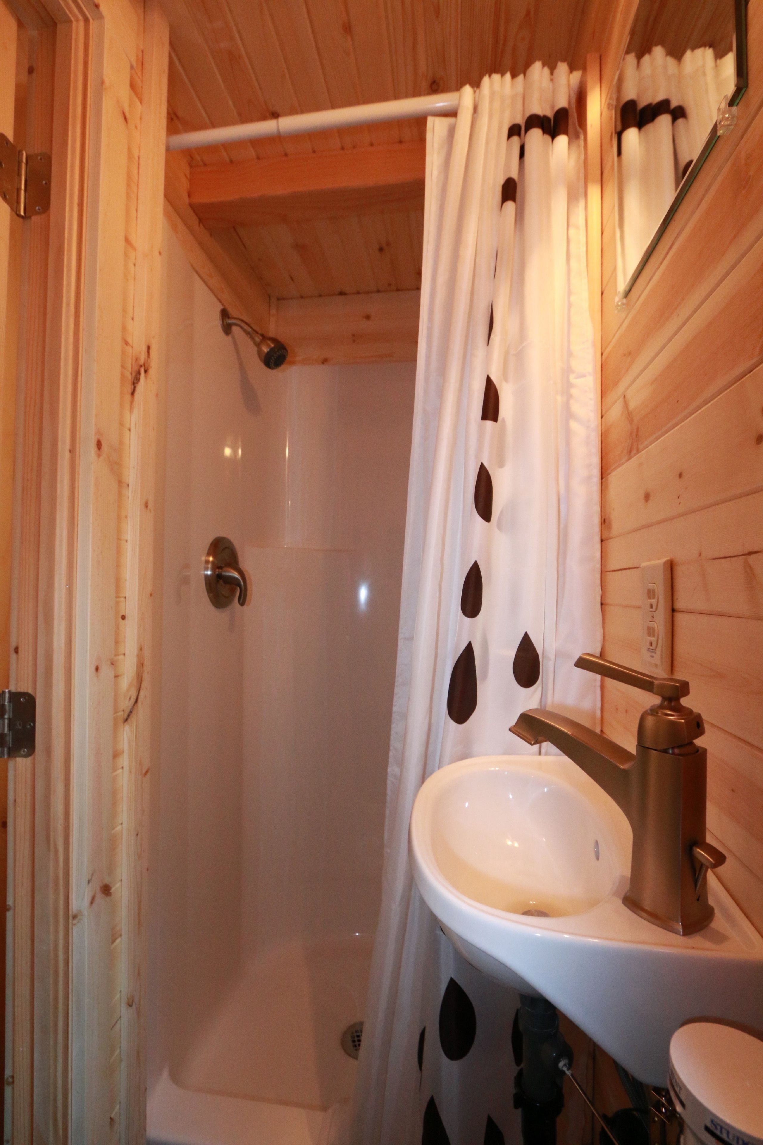 Een houten badkamer in een vakantiehuis, met een douche, wastafel en toilet.