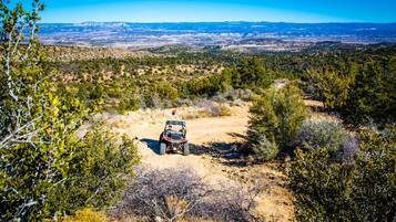 A quad bike on a dirt path surrounded by sparse vegetation and distant mountains.